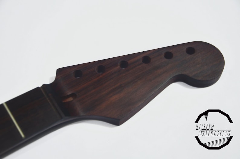 May include: A dark brown guitar neck with a headstock featuring six tuning peg holes. The neck has a fretboard with white inlays. The logo "3 Hitz Guitars" is visible in the bottom right corner.