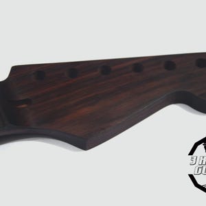 May include: A dark brown guitar headstock with six tuning peg holes. The wood grain is visible, and the headstock has a curved shape. The logo for 3 HIC GUITARS is in the lower right corner.