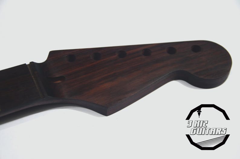 May include: A dark brown guitar headstock with six tuning peg holes. The wood grain is visible, and the headstock has a curved shape. The logo for 3 HIC GUITARS is in the lower right corner.