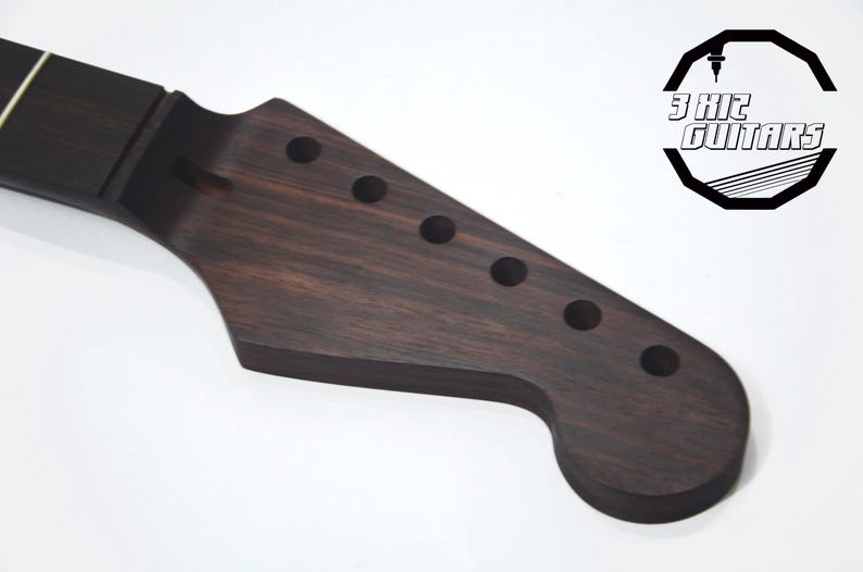 May include: A dark brown guitar neck with six tuning peg holes. The neck is made of wood and has a smooth finish. The logo for "3 Kit Guitars" is in the upper right corner.