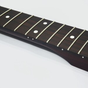 May include: Close-up of a guitar fretboard with silver frets and white dot inlays. The dark wood has a rich grain pattern. The logo "3 KHz GUITARS" is in the upper right corner. This is a guitar part.