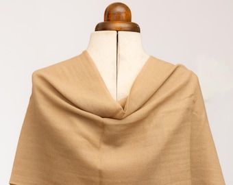 May include: A solid tan scarf with a fine herringbone weave pattern draped over a mannequin. The fabric has a soft, matte texture and a consistent light brown color throughout, showing subtle diagonal lines across the entire surface of the textile.