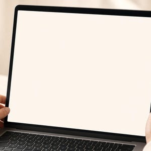 K&ouml;nnte beinhalten: Ein silberner Laptop mit einem d&uuml;nnen schwarzen Rahmen und einem gro&szlig;en, leeren, cremewei&szlig;en Bildschirm. Das Ger&auml;t verf&uuml;gt &uuml;ber eine Standard-QWERTY-Tastatur mit schwarzen Tasten und ist im Querformat ausgerichtet, was eine leere Arbeitsfl&auml;che zeigt.