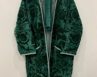 May include: A dark green robe with a floral pattern and white trim, hanging on a wooden hanger. The robe has long sleeves and pockets. The interior lining is striped.