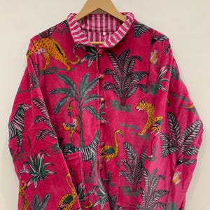 May include: A vibrant pink jacket with a jungle-themed pattern featuring zebras, leopards, and palm trees. The jacket has a button-up front and a striped collar. The lining is a striped pattern.