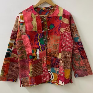 May include: A patchwork jacket in shades of red, pink, and gold, with a quilted texture. The jacket features a mandarin collar, long sleeves, and a button-up front. The design incorporates various fabric patterns and textures.