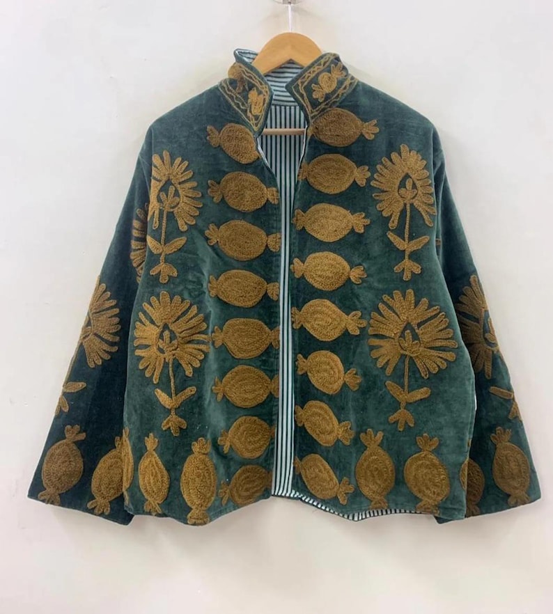 May include: A dark teal jacket with gold-colored embroidered floral and oval designs. The jacket has a mandarin collar and a striped lining. The jacket is hanging on a wooden hanger against a white background.