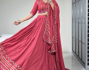 May include: A flowing, red skirt and top set with gold and white striped trim. The top has a V-neck and short sleeves. The set includes a matching scarf. The outfit is a traditional style.