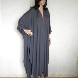 May include: A long, gray, loose-fitting, open-front cardigan with long sleeves. The cardigan is made of a soft, drapey fabric.