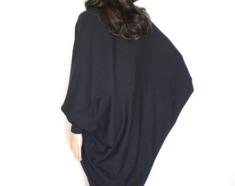 May include: A black, long-sleeved, oversized sweater with a draped, asymmetrical design. The sweater is made of a soft, knit fabric.