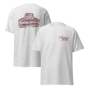 Könnte beinhalten: Zwei hellgraue T-Shirts. Eines zeigt eine weinrote Grafik eines Oldtimer-Ford-Trucks auf der Rückseite. Das andere hat den Text "American Classic" in weinroter Schrift auf der Vorderseite.