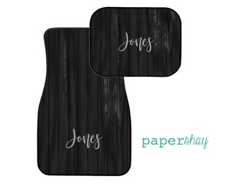 May include: Two black car floor mats with a wood grain pattern and the name "Jones" in white text. The mats are from the company "papershay".