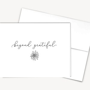 May include: A white card with the text "beyond grateful" written in black cursive script. A simple line drawing of a daisy is below the text.