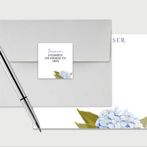 May include: A white envelope with a blue and green floral return address label. The label says "Dawson, 2 Flower St, Los Angeles, CA 10078". A white notecard with a blue and green floral design and the text "SER" in the top right corner.