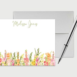 May include: Personalized stationery featuring a watercolor floral border with pink, yellow, and orange flowers. The name "Melissa Jones" is printed in green script at the top of the card.
