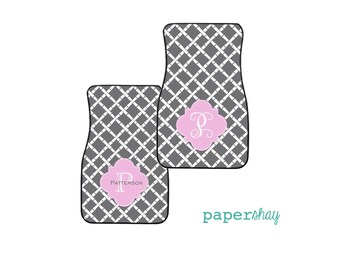 May include: A set of two gray car floor mats with a white criss-cross pattern. The mats feature a pink monogram with the letter "P" and the name "Patterson".