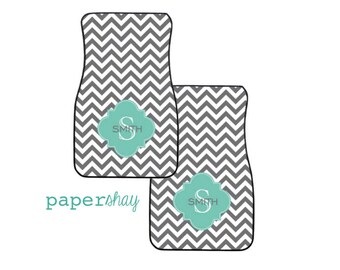 May include: Two gray and white chevron patterned car floor mats with a teal monogrammed initial "S" in a decorative frame. The monogram reads "Smith".