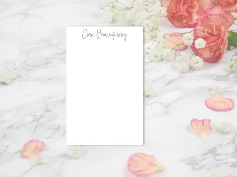 May include: A white notepad with the name "Cora Hemingway" written in cursive at the top.