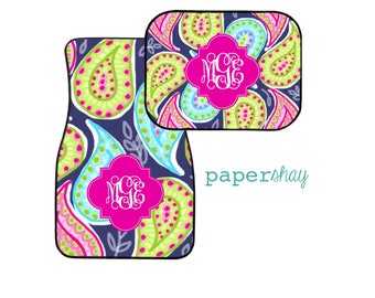 May include: Two car floor mats with a paisley pattern in shades of pink, green, blue, and white on a navy blue background. The mats feature a monogram in a pink circle.