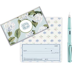 May include: A set of blue and white checkbook covers with a floral design and a matching blue fountain pen. The checkbook cover has a monogrammed initial in the center.