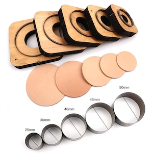 Könnte beinhalten: Lederhandwerkzeug-Set. Enthält hölzerne Kreisschneider mit Metallklingen und verschiedene Größen von Metallkreisschneidern, von 25 mm bis 50 mm. Außerdem sind mehrere vorgeschnittene Lederkreise abgebildet.
