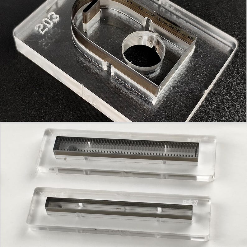Pu&ograve; includere: Modelli in acrilico trasparente con inserti metallici. Un modello ha il numero "203" inciso sulla superficie. Di seguito sono mostrati due modelli aggiuntivi, ciascuno con un inserto metallico. I modelli sono su uno sfondo bianco e nero.
