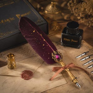 May include: A deep burgundy feather quill pen with gold speckles, featuring a gold metal handle, a purple gemstone accent, and a brown ribbon. The set includes a black ink bottle labelled Magic Power, a gold thimble, and four metal nibs.