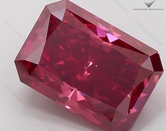 Op de afbeelding: Een rechthoekige edelsteen met radiant-slijpvorm in een diepe, levendige rode kleur met meerdere facetten die het licht reflecteren. De steen heeft een hoogglanzende afwerking en staat in een hoek. De tekst DND DIAMONDS is in de hoek zichtbaar.