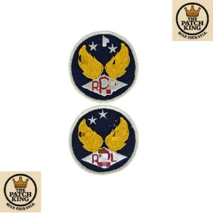 Peut inclure: Deux écussons ronds avec un fond bleu marine, des ailes dorées et des étoiles blanches. Les écussons ont une bordure blanche et un motif rouge et blanc au centre. Le texte "THE PATCH KING RULE YOUR STYLE" est dans un cercle.