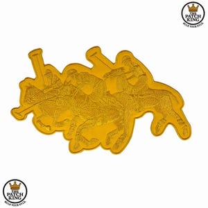 May include: A gold-coloured patch depicting a polo match with riders on horseback. The patch shows a detailed design of polo players in action, with the text "THE PATCH KING" and "RULE YOUR STYLE" in a circular logo.