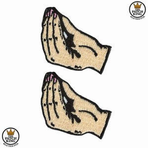 May include: Two embroidered patches depicting a hand gesture with a beige skin tone, black outlines, and pink fingernails. The patches are in the shape of a hand with the fingers and thumb touching. The text "THE PATCH KING" is printed on the bottom of the patch.