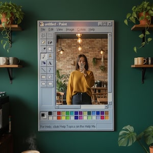 Könnte beinhalten: Ein rechteckiger Spiegel, der wie die Oberfläche des Programms "Paint" gestaltet ist. Der Spiegel reflektiert eine Person, die ein Selfie macht. Der Text "untitled - Paint" steht oben, mit einer Werkzeugleiste links und einer Farbpalette unten. Der Spiegel ist an einer dunkelgrünen Wand befestigt.