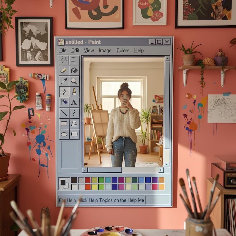 May include: A unique mirror designed to resemble a computer paint program window, with the text "untitled - Paint" at the top. The mirror reflects a person in a cream-colored sweater and jeans. The wall is painted a coral color and decorated with art and paint supplies.