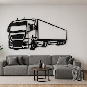 May include: Black metal wall art depicting a lorry. The artwork shows a detailed front cab and a large trailer. It's mounted on a white wall above a grey sectional sofa, creating a modern aesthetic.