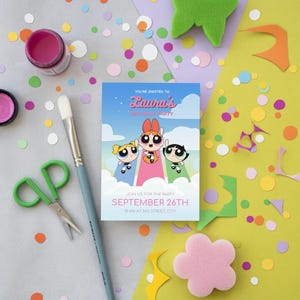 Puede incluir: Una invitación de cumpleaños con las Supernenas. La invitación tiene un fondo de cielo azul con el texto "Laura's Birthday Party" y la fecha "26 de septiembre". La imagen está rodeada de confeti colorido, pintura y materiales de manualidades.