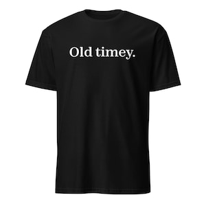 May include: Black t-shirt with the white text "Old timey." The shirt has short sleeves and a crew neck. The text is in a simple, sans-serif font.