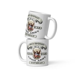 May include: Two white ceramic mugs stacked. Each mug has the text "PROUD DESCENDANT OF A CIVIL WAR UNION ARMY VETERAN" around a central emblem of an eagle holding a banner with the American flag.