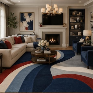 May include: A living room featuring a cream-colored sectional sofa with red and navy blue accent pillows. A large, colorful rug with red, white, and blue curved stripes dominates the floor. The room includes a fireplace, a TV, and two navy blue armchairs.
