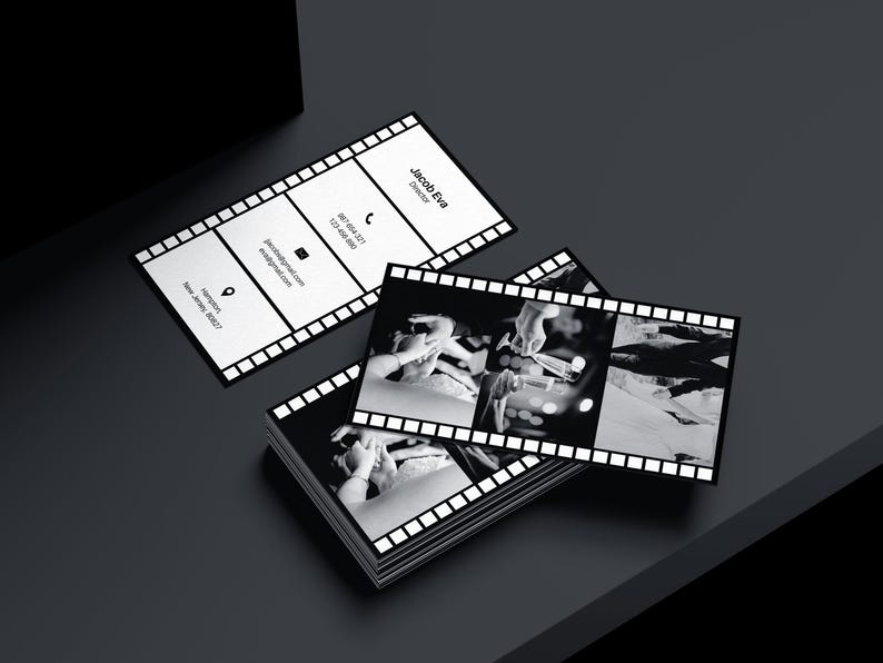 Puede incluir: Tarjetas de visita con dise&ntilde;o de tira de pel&iacute;cula. Las tarjetas son en blanco y negro, con el nombre "Jacob Eva, Director" impreso. Tambi&eacute;n se incluye informaci&oacute;n de contacto. Se ve una pila de tarjetas.