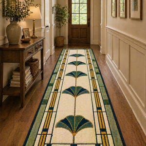 May include: A long rectangular runner rug featuring a cream-colored center with a repeating pattern of teal and dark blue fan-shaped motifs. The rug is bordered by geometric lines in shades of green, yellow, and dark blue, creating a structured design.