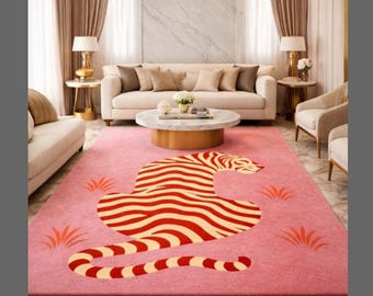 May include: A pink rug featuring a tiger design in red and cream. The rug is placed in a living room with a sofa, chairs, and a coffee table. The room is decorated with a chandelier and curtains.
