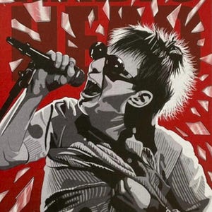 May include: Illustration of a singer with sunglasses and a microphone, set against a red background. The word "RADIO HEAD" is displayed in bold, dark letters. The image has a graphic style with shattered glass effects.