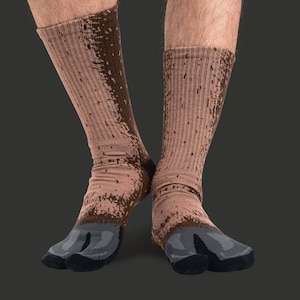 May include: A pair of brown and tan socks with a split toe design. The socks have a textured appearance with darker brown accents. The toe and sole areas are grey and black. The socks are ribbed and extend up the calf.