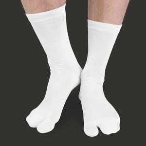 May include: A pair of white tabi socks, designed with a split toe. The socks are made of a soft, opaque material and reach mid-calf. The background is a solid dark gray.