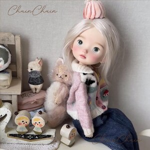 Whimsical doll outfit featuring multicolor blocks and embroidered cardigan