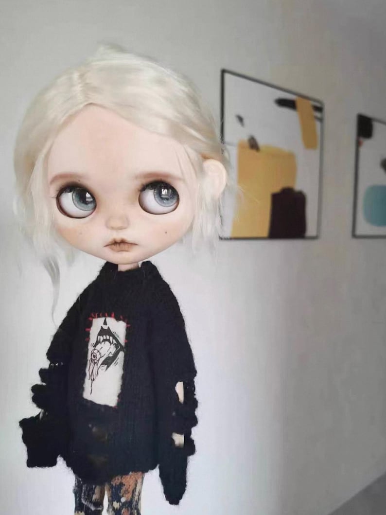 Close-up of embroidered monster face on black knit sweater for dolls