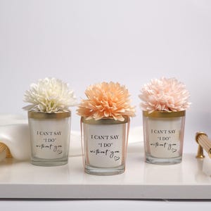 May include: Three glass candle holders with gold rims and floral accents, arranged on a white tray with gold handles. Each candle has the text "I CAN'T SAY 'I DO' without you" printed on it, with a small heart symbol.