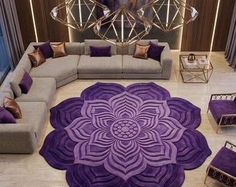 May include: A large, circular, purple area rug featuring a raised, symmetrical lotus flower pattern. The rug is centered in a room with a light gray sectional sofa, two purple velvet armchairs, and three geometric gold pendant lights.