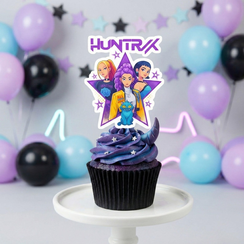 May include: A cupcake with purple frosting and a decorative topper featuring three cartoon women and the word "HUNTRAX" in purple. The cupcake is on a white cake stand, with balloons in the background.