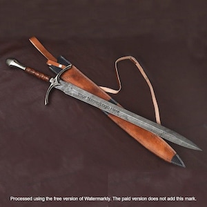 Puede incluir: Una espada larga y plateada con un mango de madera marrón y una vaina de cuero. La espada tiene una guarda curva y una hoja puntiaguda. La vaina es de cuero marrón con una punta negra. El texto "Your Name/Logo Here" está en la hoja.